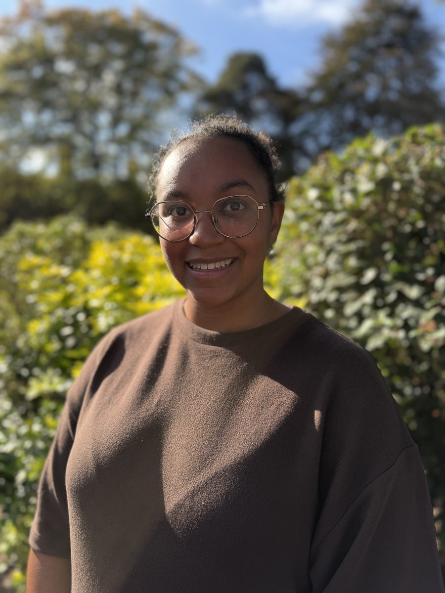 Naomi Pink, Deputy Manager, smiling outdoors in front of a green hedge.