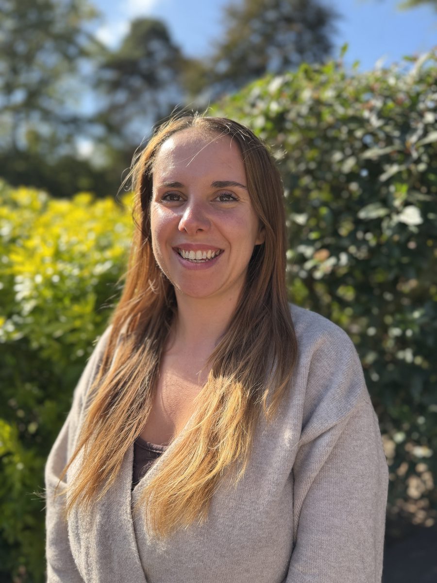 Sophie Lemon, Nursery Manager, smiling outdoors in front of a green hedge.